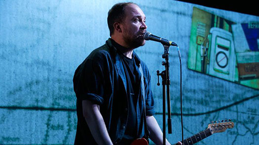 Man at microphone holding a guitar